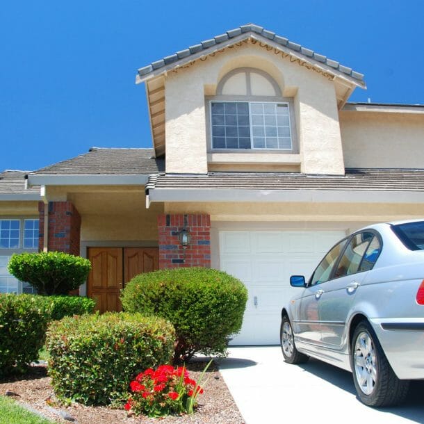 Large House with Shrubs and Car Parked in Driveway